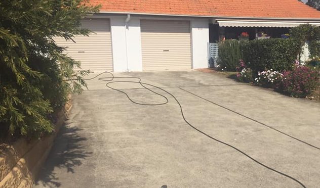 single story home with driveway being pressure cleaned