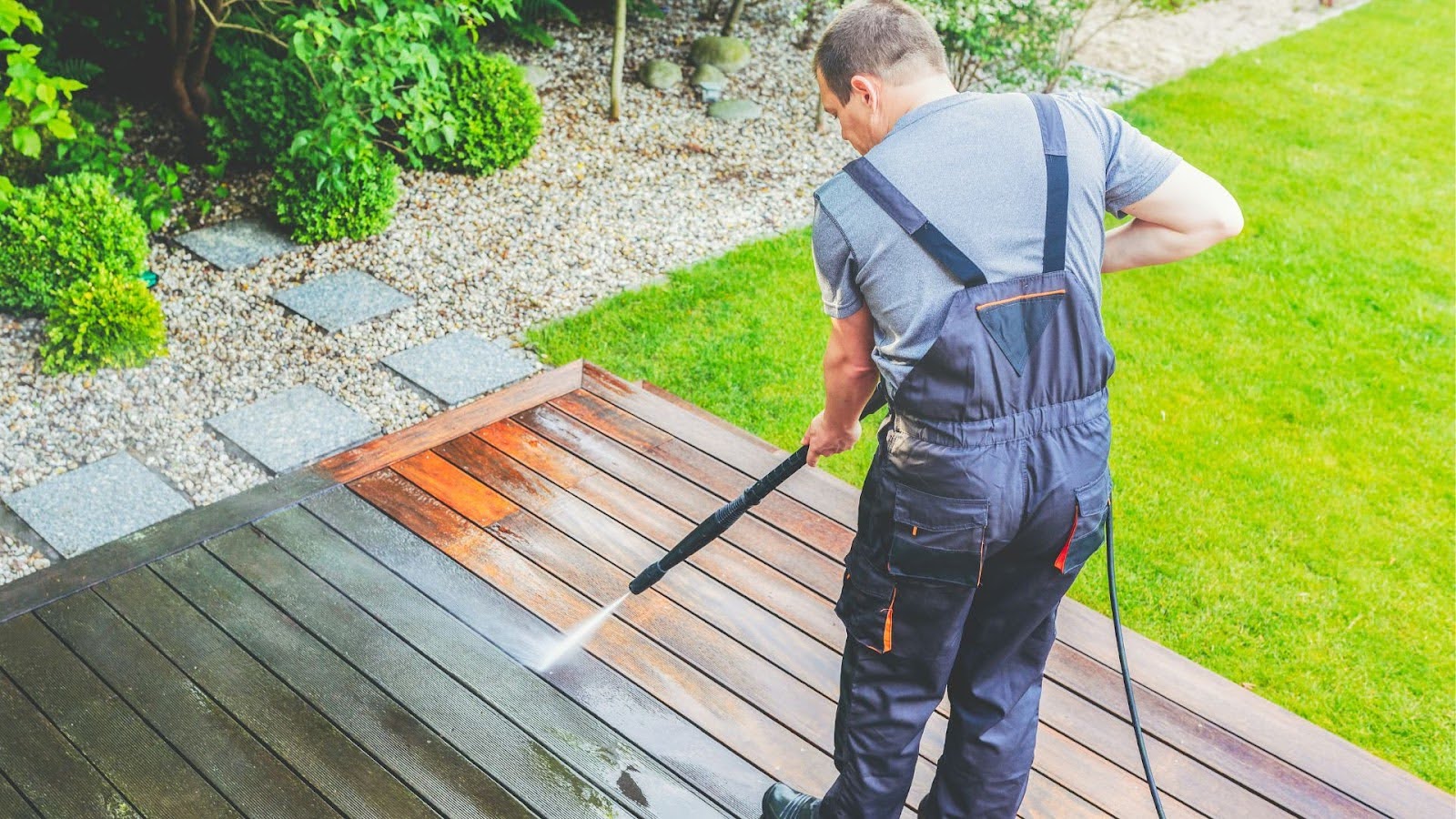 Deck cleaning technician uses a soft pressure washer to remove dirt and grime from a wooden patio deck, restoring its natural beauty and extending its longevity.