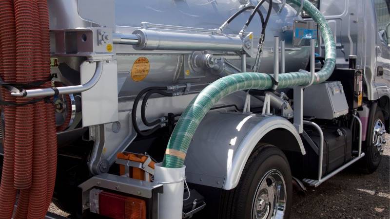 etailed view of a vacuum truck’s equipment, showing the intricate setup of hoses connected to the shiny metal tank, essential for industrial cleaning operations.