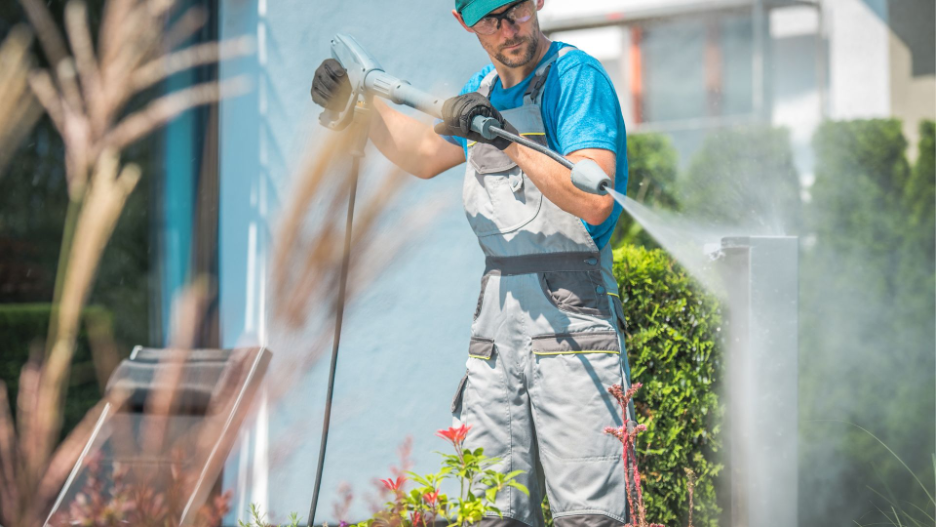 Commercial power wash technician in action, using a high-pressure nozzle to clean outdoor surfaces, showcasing the effectiveness of professional pressure cleaning services.