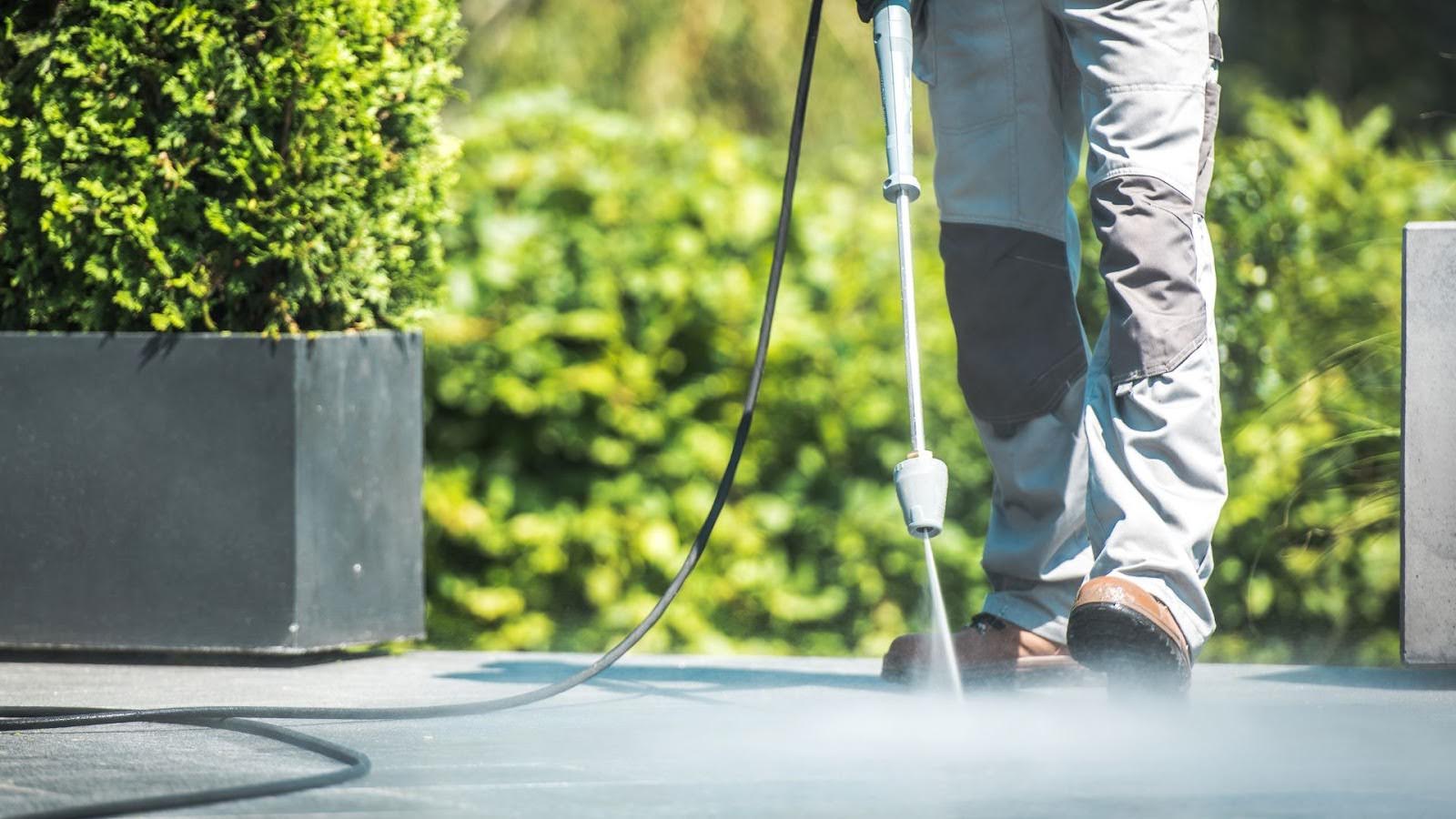 Pressure cleaning technician efficiently cleaning an outdoor surface, showcasing the power of high-pressure water cleaning.