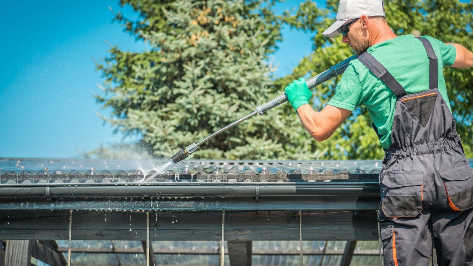 Professional gutter cleaning service technician power washing a residential gutter, removing leaves and debris to ensure efficient water flow and protect against water damage. 