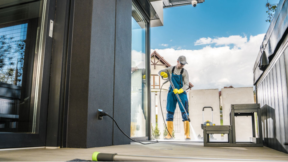 Commercial power washing professional meticulously cleans a residential entranceway, enhancing the home’s curb appeal with advanced pressure washing equipment.