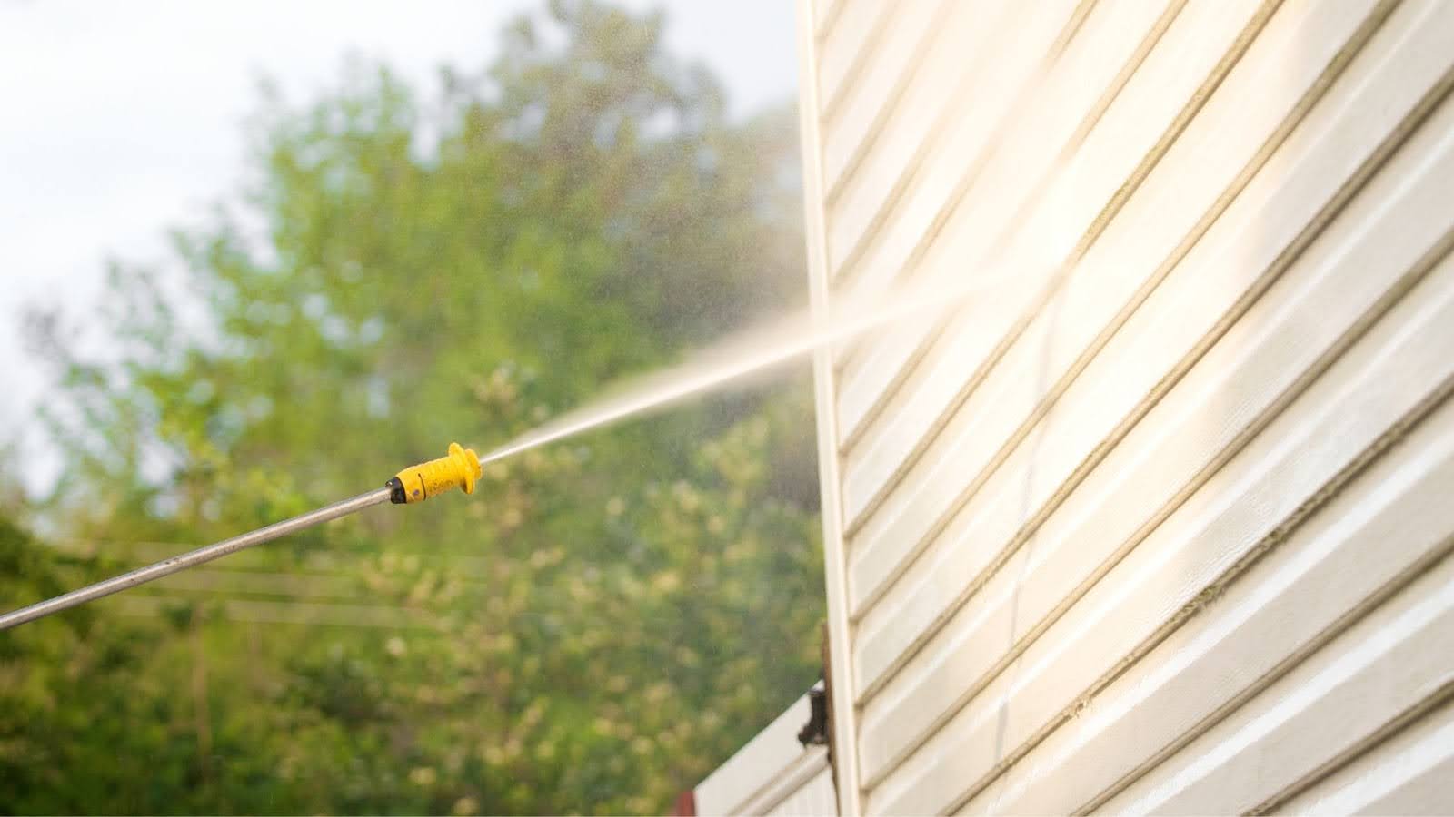 Soft washing nozzle emitting a gentle spray to clean house siding, effectively removing dirt without damaging the surface, exemplifying safe and efficient cleaning techniques.