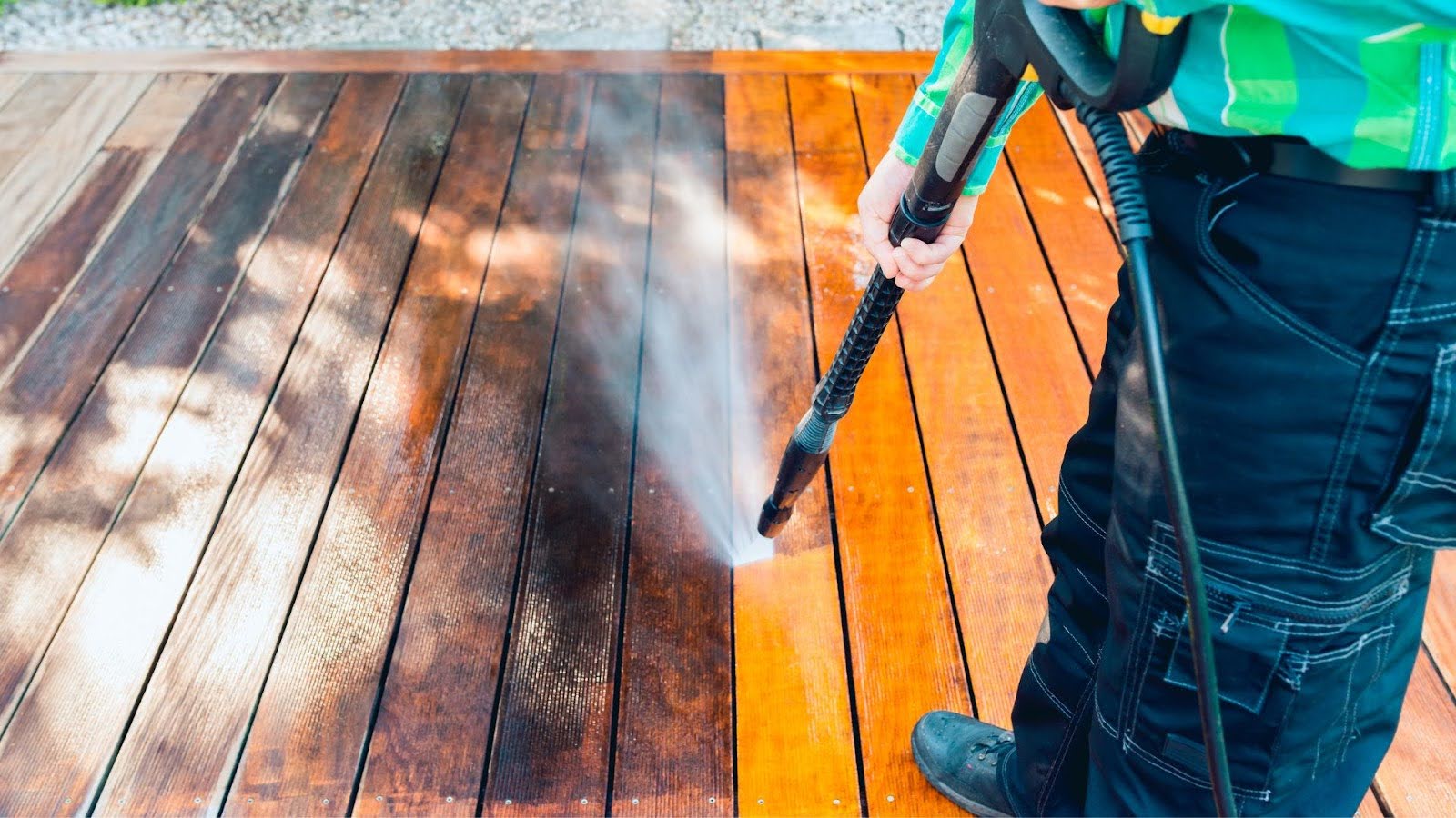 Professional performing soft washing on a wooden deck, utilising low pressure to deeply clean and rejuvenate the wood without causing any damage.