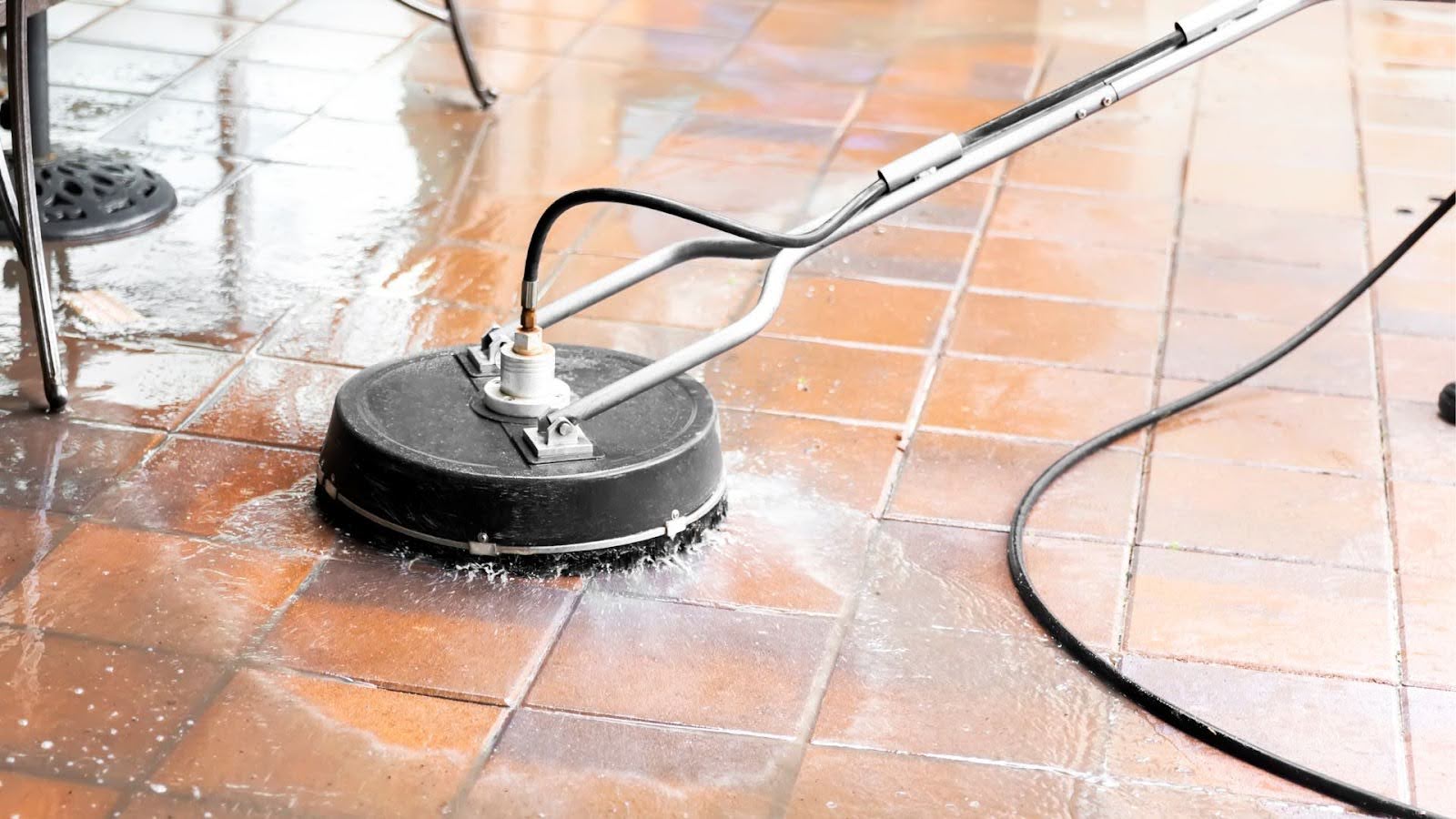 Surface cleaner attachment glides over terracotta tiles, with pressurised water spraying out to efficiently clean and enhance the tile surface's appearance.